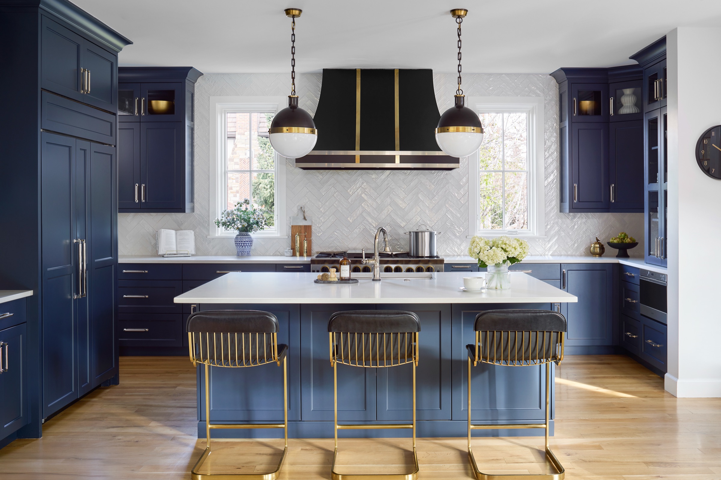 Navy blue kitchen with white quartz island, brass-and-black barstools, and hood pendants — Bonnie Brae whole home renovation in Denver