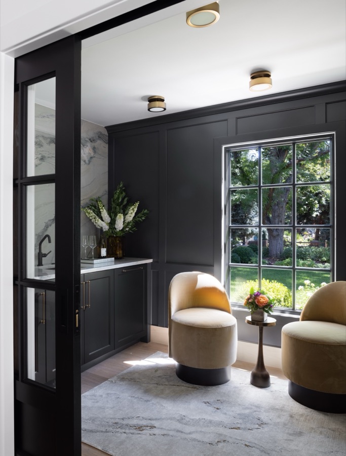 Office lounge with black paneled walls, cream ottomans, and black-framed glass doors — Greenwood Village hidden-detail whole home renovation