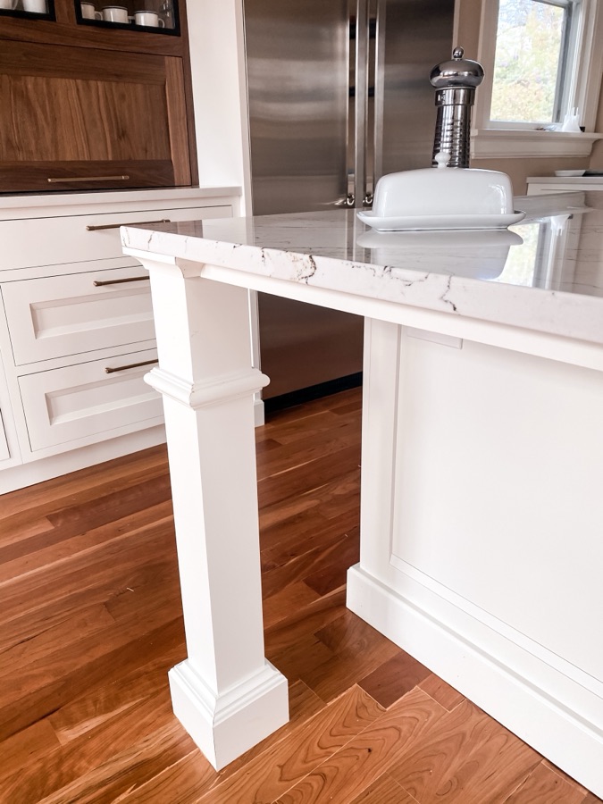 Island leg detail with walnut accents and stainless fridge beyond — historic Colorado Springs kitchen remodel