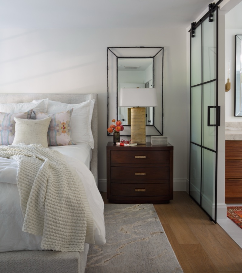 Primary bedroom with sliding black-framed glass doors and soft neutral bedding — Greenwood Village hidden-detail whole home renovation