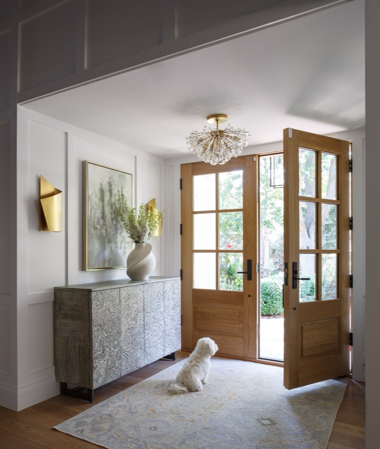 Entry with wood double doors, speckled console, and family dog on a neutral rug — Greenwood Village hidden-detail whole home renovation