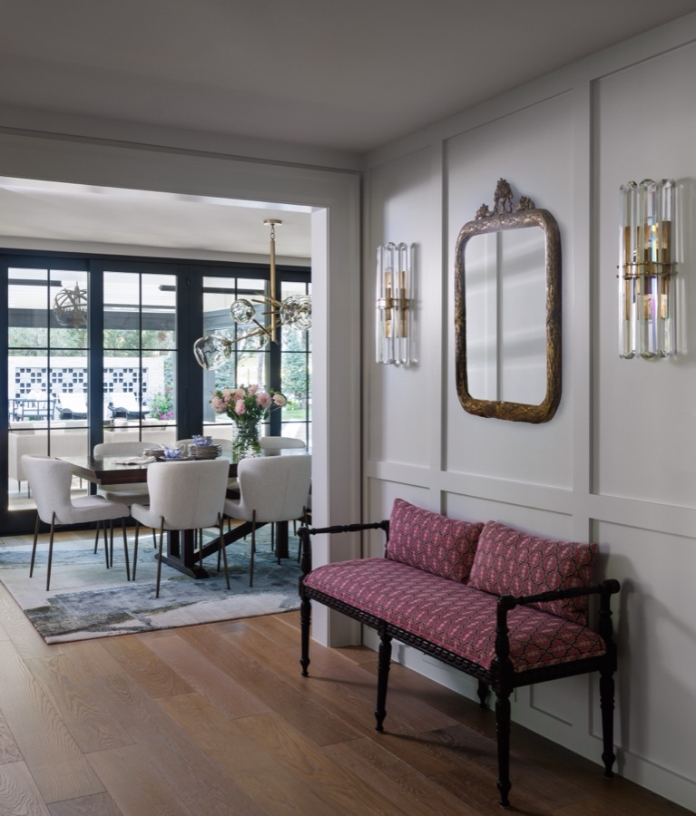 Formal sitting room with white paneling, antique bench with pink cushions, and crystal sconces — Greenwood Village hidden-detail whole home renovation