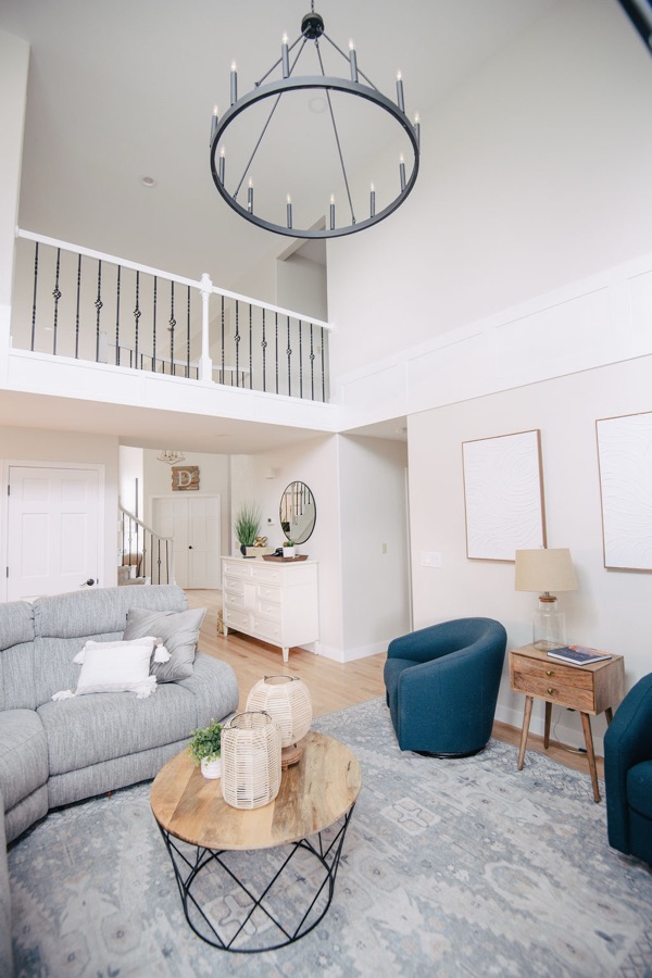 Living room with gray sectional, teal accent chairs, and balcony overlook — Stonegate main floor renovation in Parker, Colorado