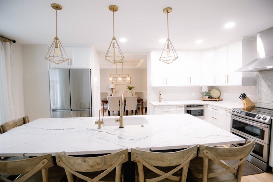 Open kitchen and dining with brass lanterns and creamy white palette — Stonegate main floor renovation in Parker, Colorado