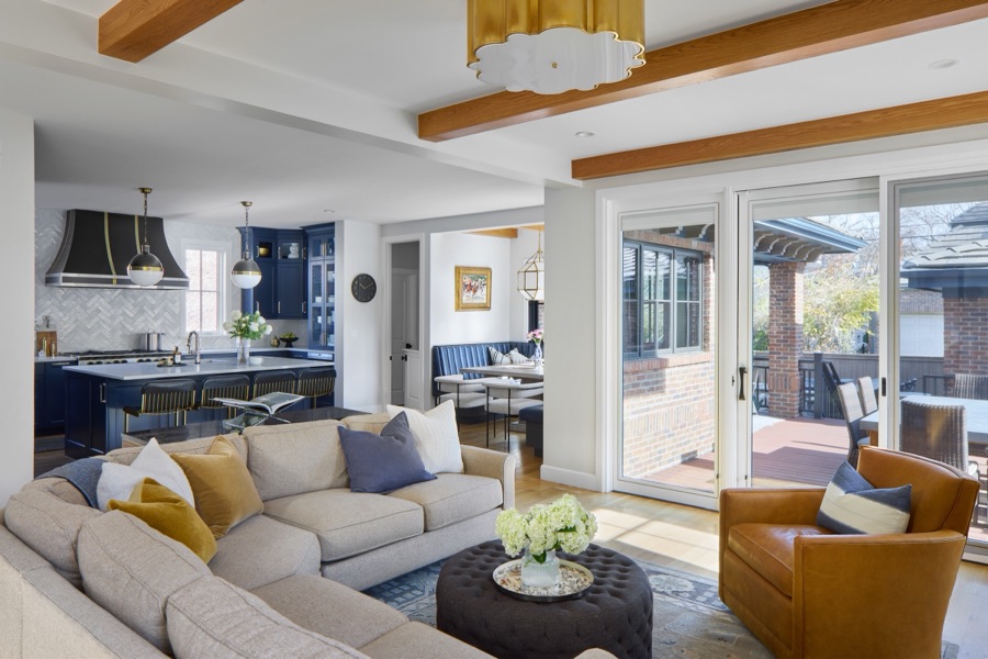Open family room with cream sectional, camel leather chairs, and view into the navy kitchen — Bonnie Brae whole home renovation in Denver