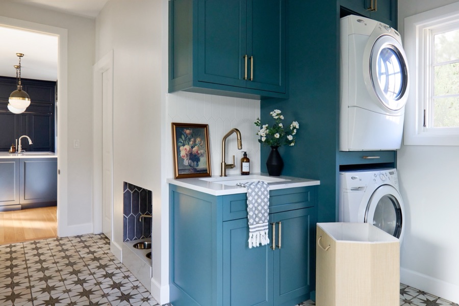 Teal laundry room with patterned cement tile and stacked washer-dryer — the renovation work praised by E+E clients