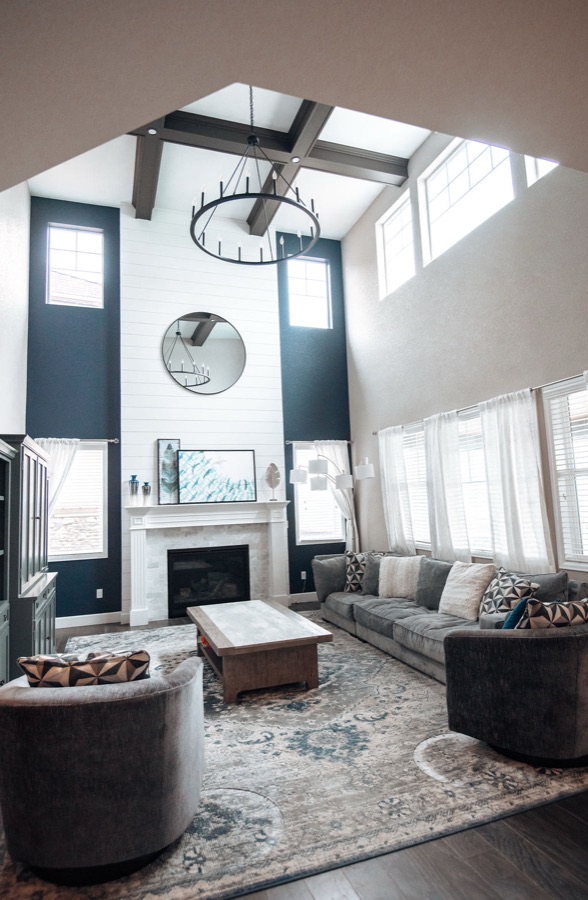 Two-story shiplap fireplace with cast mantle and iron chandelier — Blackstone family room renovation in Aurora, Colorado