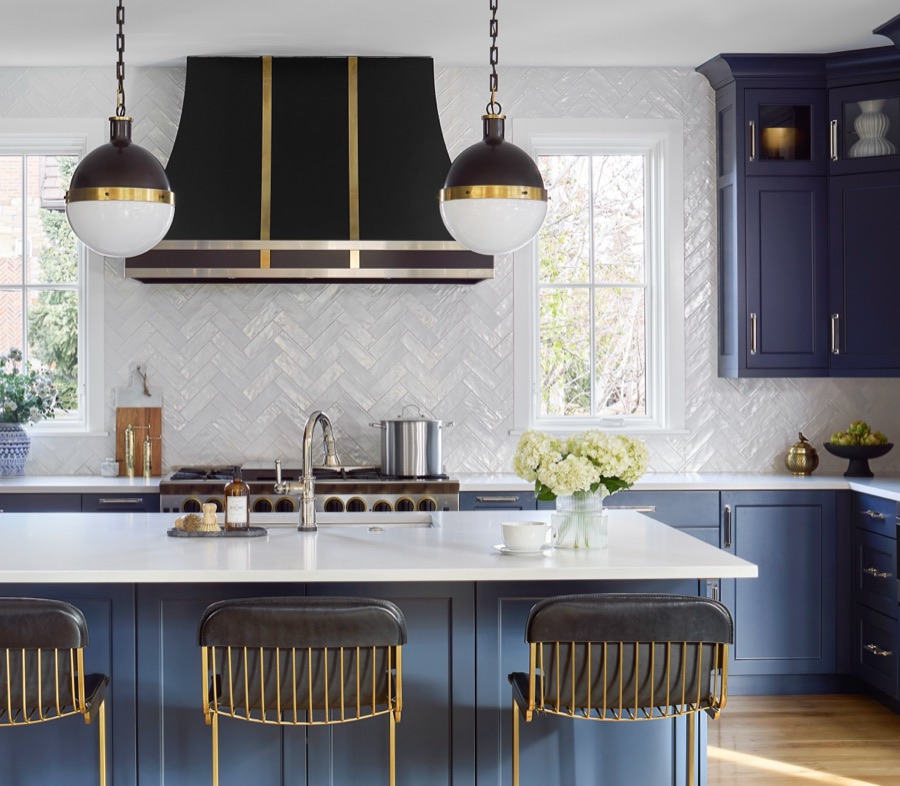 Navy kitchen island with brass barstools, black-and-gold range hood, and white herringbone tile backsplash — Bonnie Brae whole home renovation in Denver