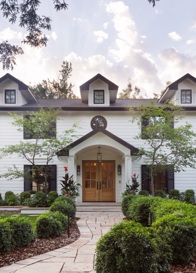 Front exterior with dormers, wood door, and manicured boxwood — Greenwood Village hidden-detail whole home renovation